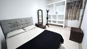 A bedroom with a bed, a wardrobe, a mirror, and a small table. - Apartamento en Valledupar (Valledupar)