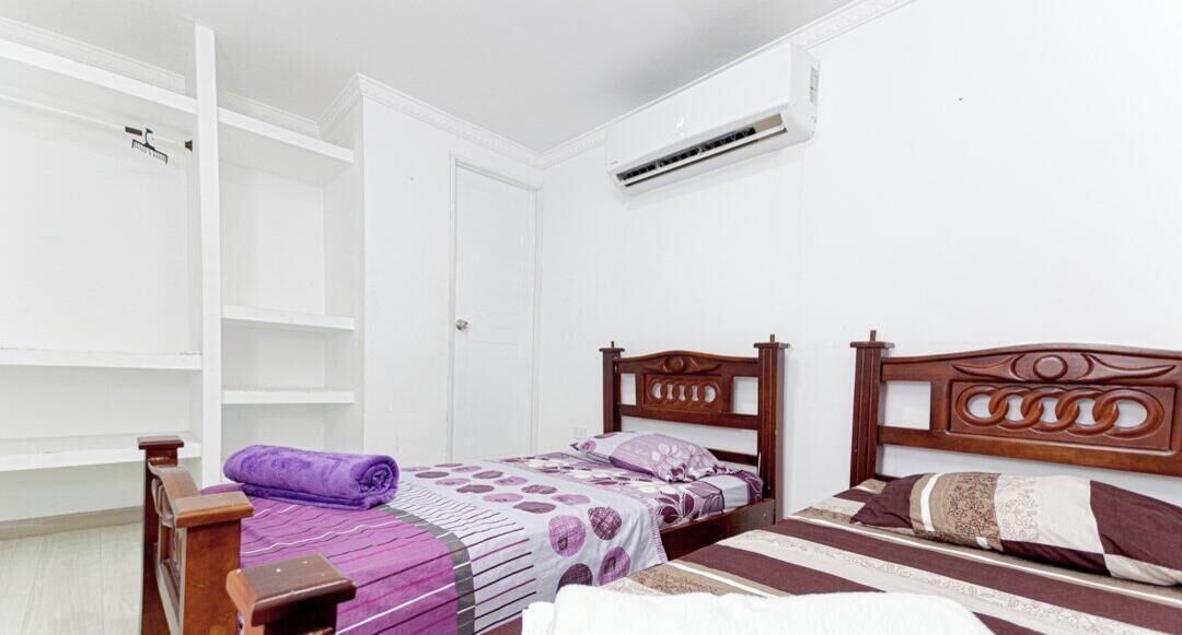 Un dormitorio con dos camas, un armario y un aire acondicionado.