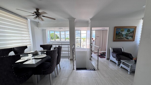A dining area with a table set for four, a ceiling fan, and a view through the window. - Apartamento en Valledupar (Valledupar)