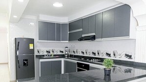 A modern kitchen with grey cabinets, a black refrigerator, and a black countertop. - Apartamento en Valledupar (Valledupar)