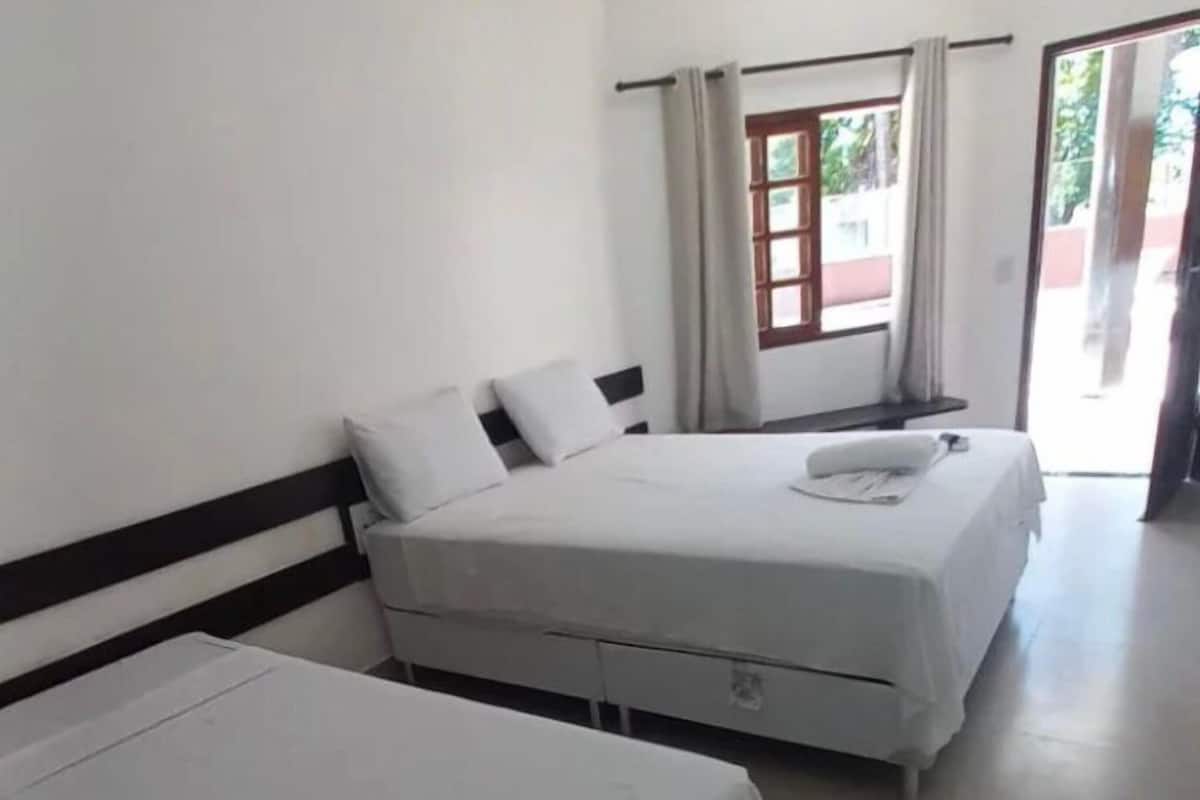 A room with two beds, a window with curtains, and a door leading outside.