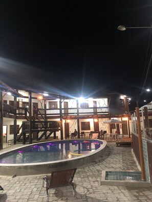 Ein Poolbereich mit Holzterrasse, Liegestuhl und Treppe zu einer erhöhten Ebene.