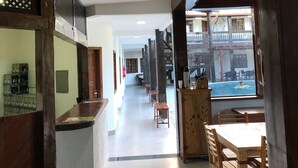 A hotel corridor with wooden furniture, a pool view, and a reception area. - Hotel Porto Brasília (Porto Seguro)
