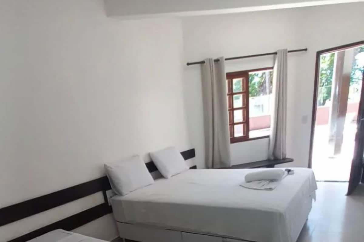 A room with two single beds, a window with curtains, and a door leading outside.