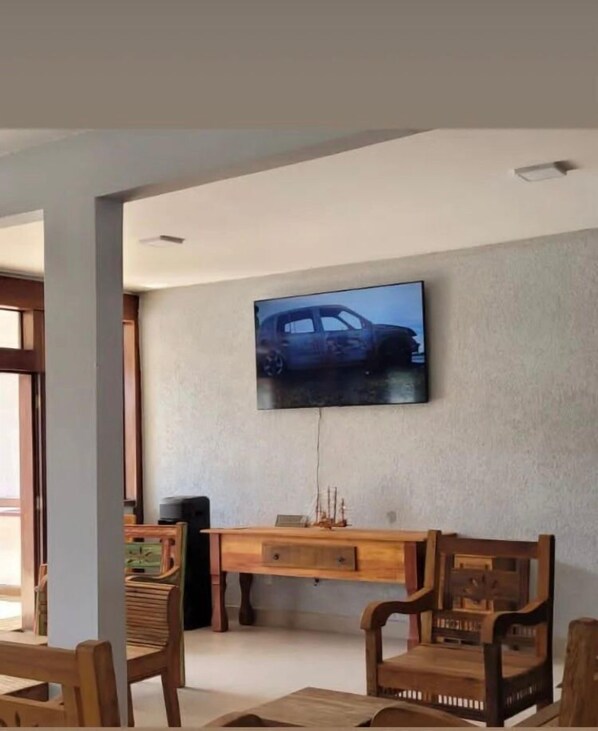 Ein Wohnzimmer mit an der Wand montiertem Fernseher, Holzmöbeln und einem kleinen Tisch mit Dekoration.