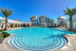 A swimming pool surrounded by buildings with a clear blue sky. - Golf course-front home with beach access, deck, grill, golf views, & streaming (Port Aransas)