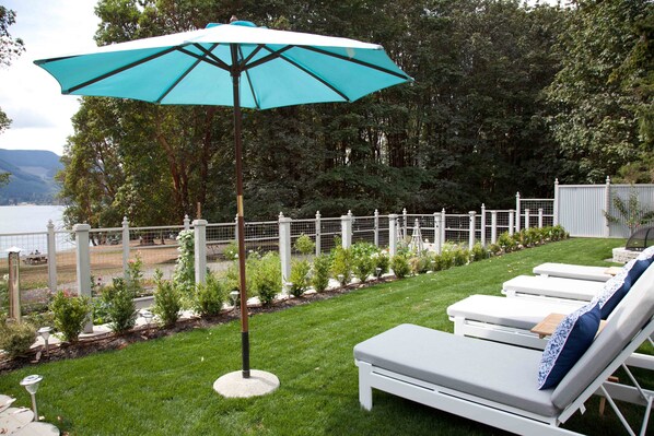 Zona de piscina con sillones de descanso y una sombrilla turquesa.