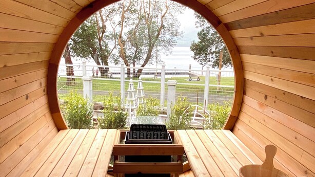 A wooden structure with a circular opening, a bench, a wooden bucket, and a grill.