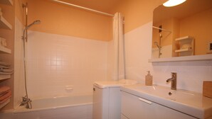 A bathroom with a bathtub, toilet, and a sink with a mirror above it. - Vue sur mer Epoustouflante (Trégastel)