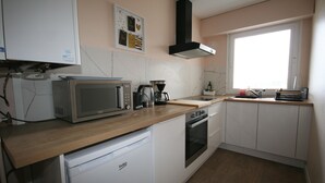 A compact kitchen with a microwave, coffee maker, and oven. - Vue sur mer Epoustouflante (Trégastel)