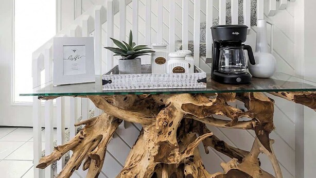 A modern kitchen with a glass coffee table, white cabinetry, and a wooden coffee table with a unique design.