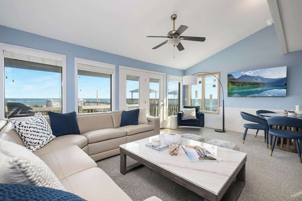 A spacious living room with a large window, a ceiling fan, and a view of the city.