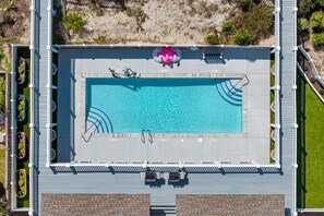 Eine Vogelperspektive eines Schwimmbeckens mit einer Poolterrasse, Liegestühlen und einem Whirlpool.