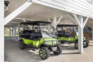 Two golf carts parked under a covered area with a concrete floor.