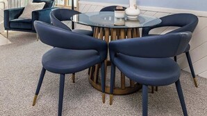 A modern dining area with a round table and six chairs, a large window with a view, and a painting on the wall.