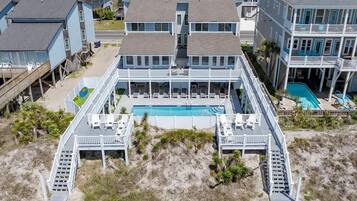 Ein Strandgrundstück mit zentralem Pool, mehreren Terrassen und einem Zugangsweg zum Strand.