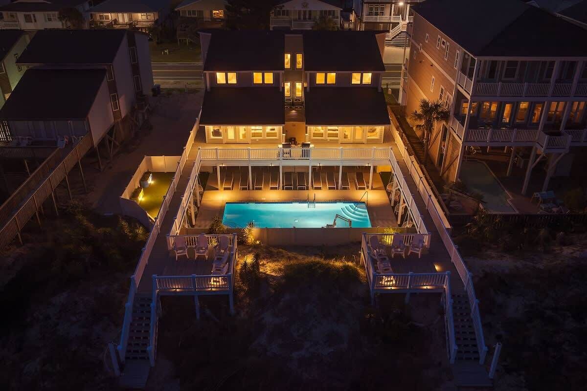 Ein zweistöckiges Gebäude mit Schwimmbad, mehreren Balkonen und einer überdachten Terrasse mit Sitzgelegenheiten.