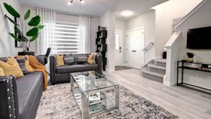 Una sala de estar moderna con sofá, mesa de centro y escalera que sube a un segundo piso.