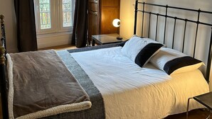 A bedroom with a bed, bedside table, lamp, and a tall wooden cabinet. - Renovated terrace apartment in Montmartre (Paris)