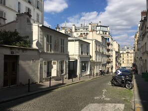 Eine enge Kopfsteinpflasterstraße gesäumt von historischen Gebäuden, einige mit Balkonen und Fensterläden.