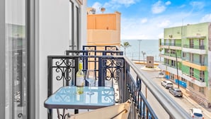 A balcony with a table and chairs, overlooking a street with parked cars and buildings. - Casa Barros Vacation Condos (Mazatlán)