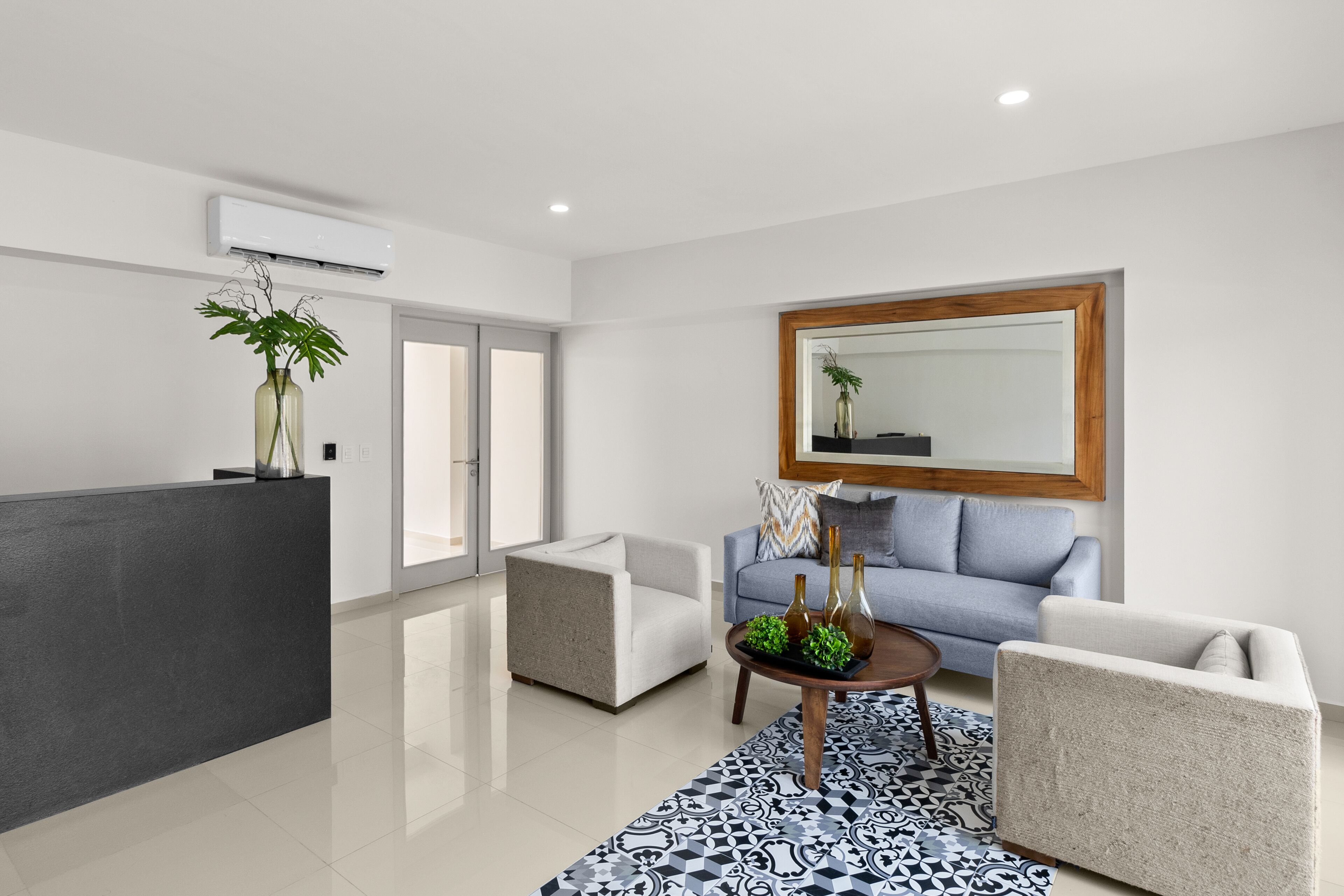 Een moderne woonkamer met een grijze bank, een bijzettafeltje en een kamerkleed met dessin.
