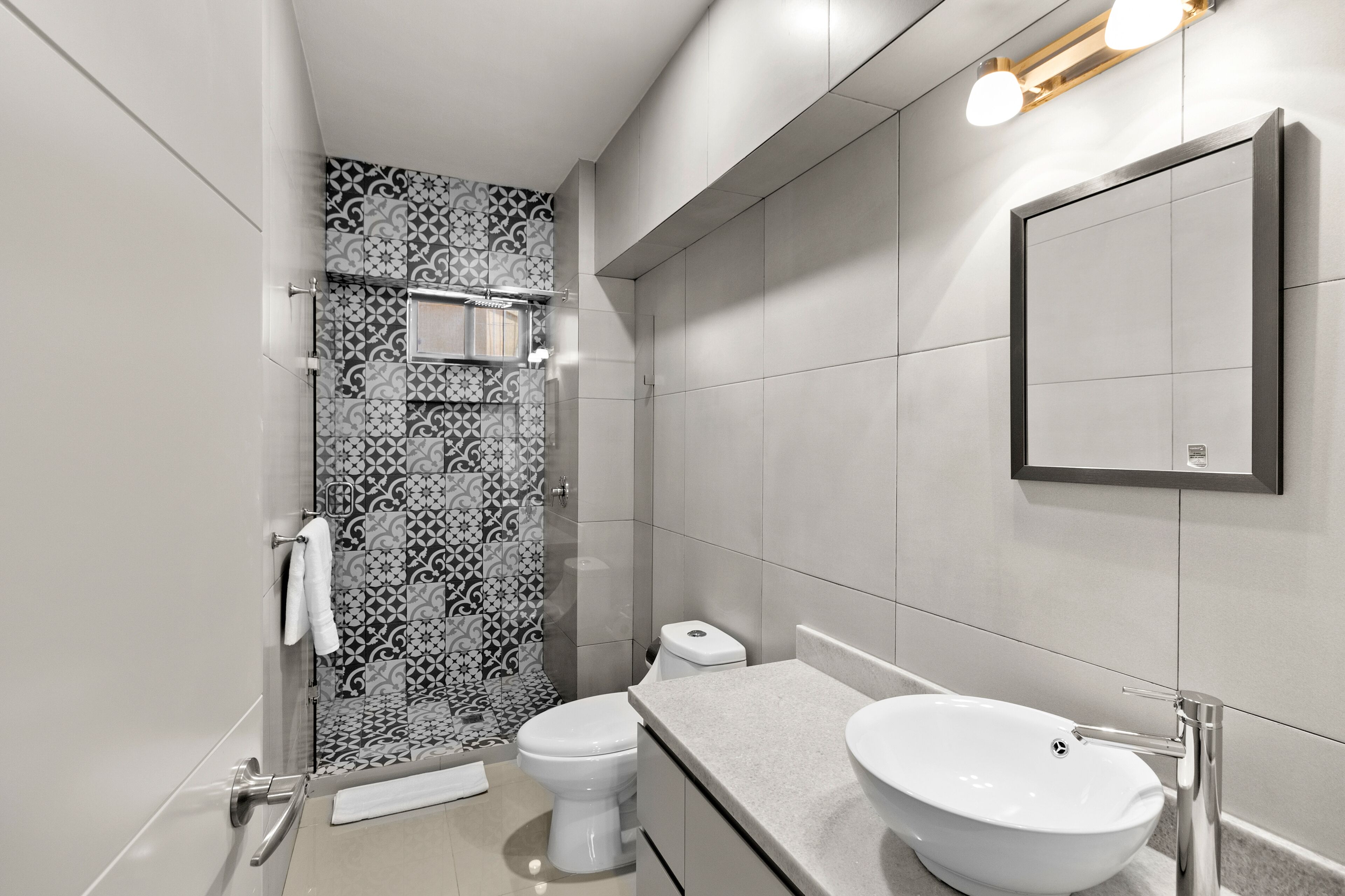 A modern bathroom with a shower, toilet, and sink.