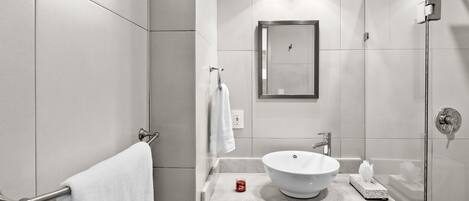 A modern bathroom with a large mirror, a white sink, and a glass shower enclosure.