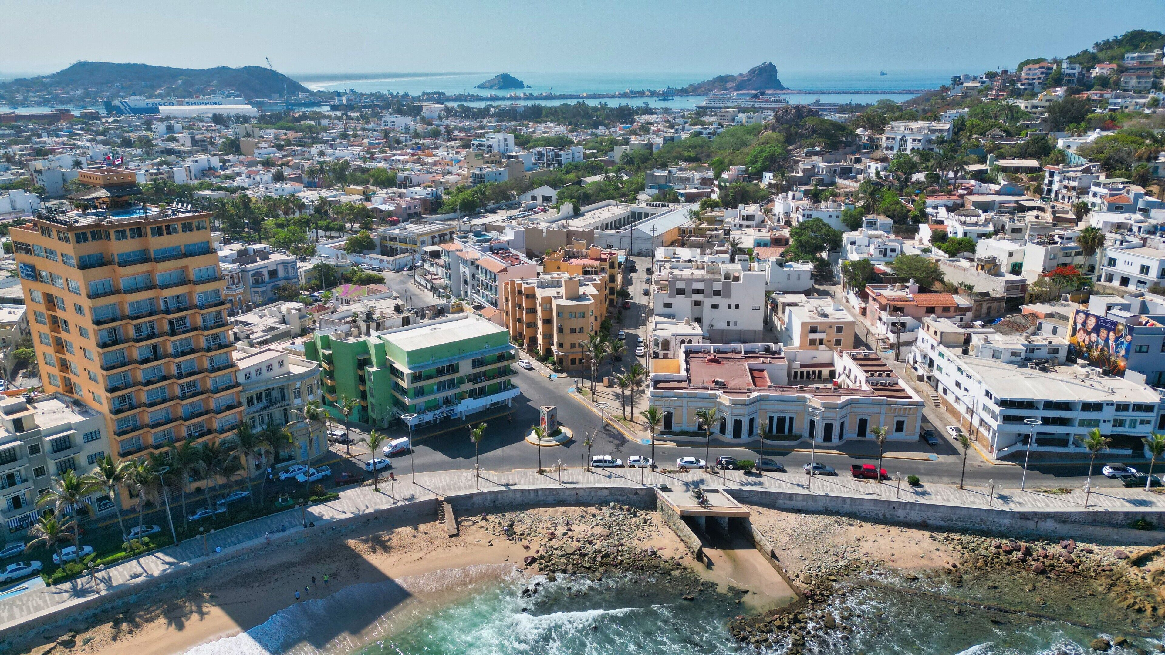 Un paisaje urbano costero con una combinación de edificios residenciales y comerciales, una playa y un litoral rocoso.
