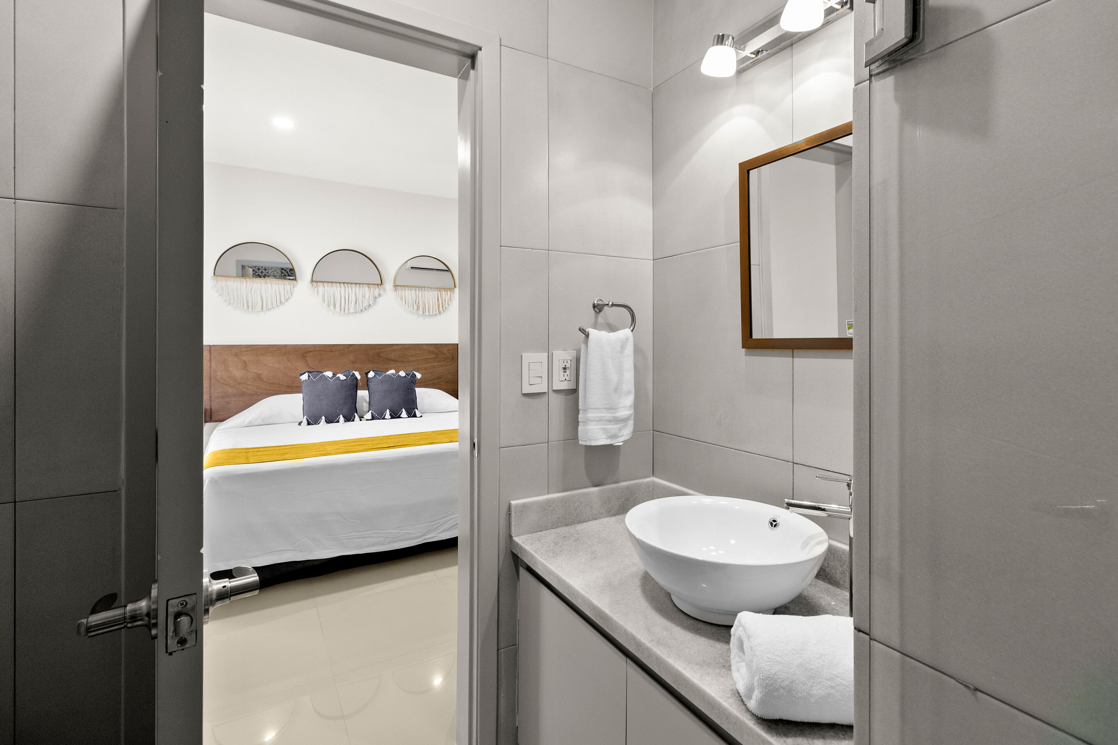 Un baño moderno con un lavabo blanco grande, un espejo y una toalla colgada en la pared.