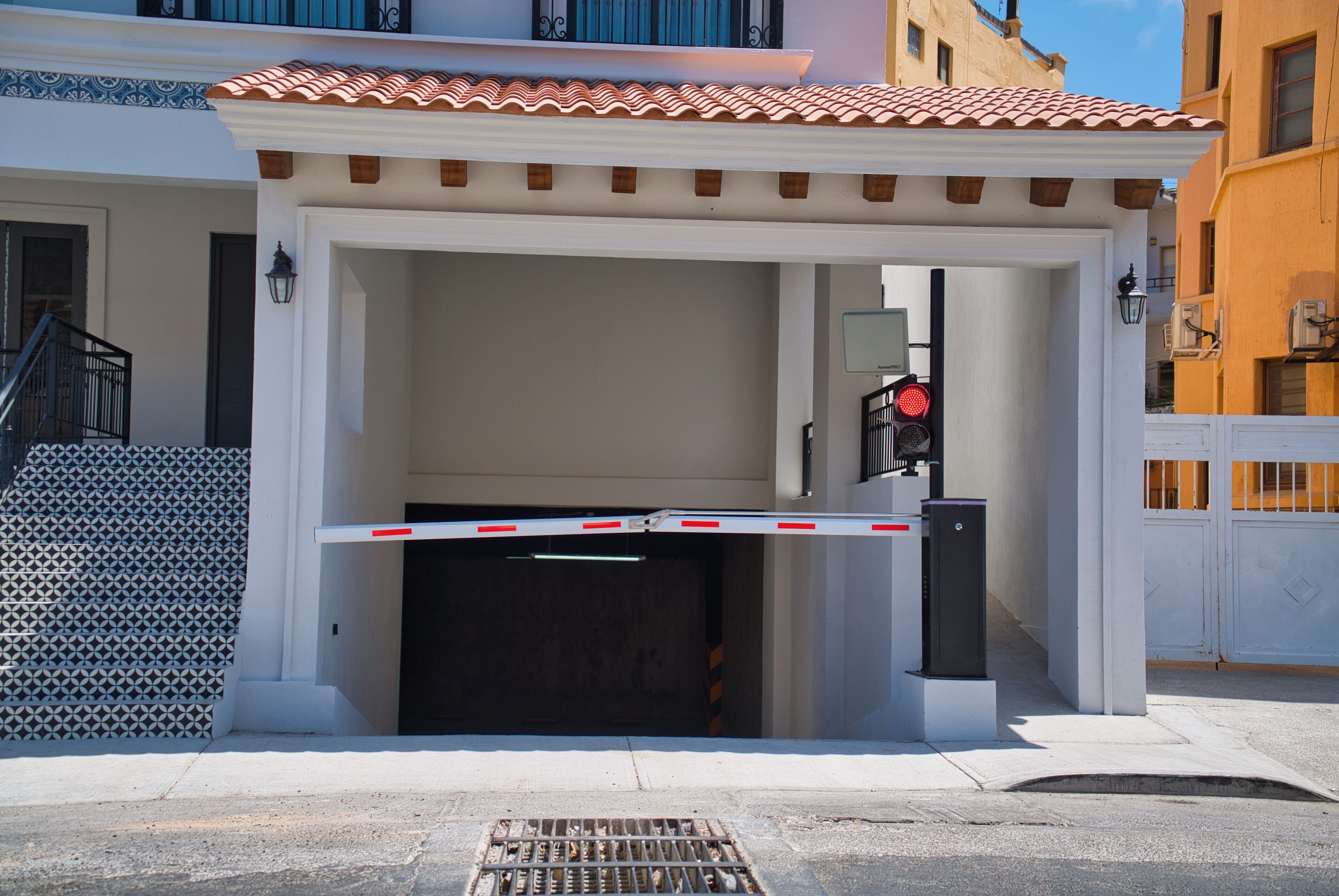 A gated entrance with a metal gate, a staircase, and a building with a tiled roof.