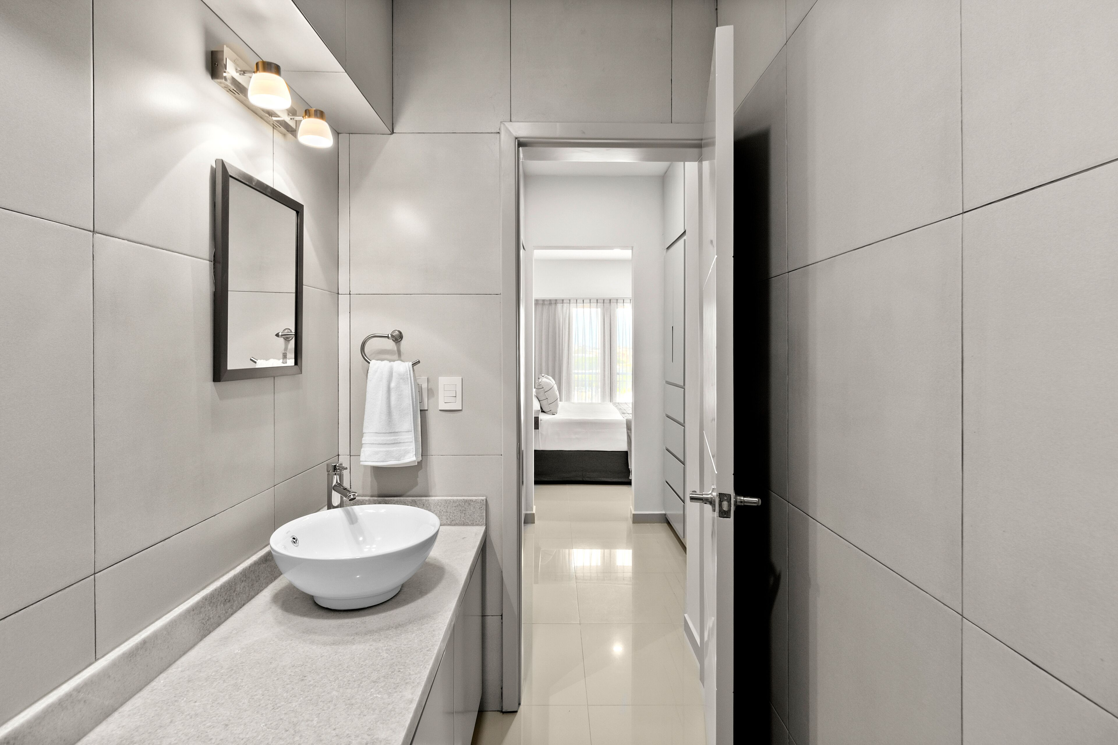Un bagno moderno con un lavandino ampio, uno specchio e un portascopevoli.