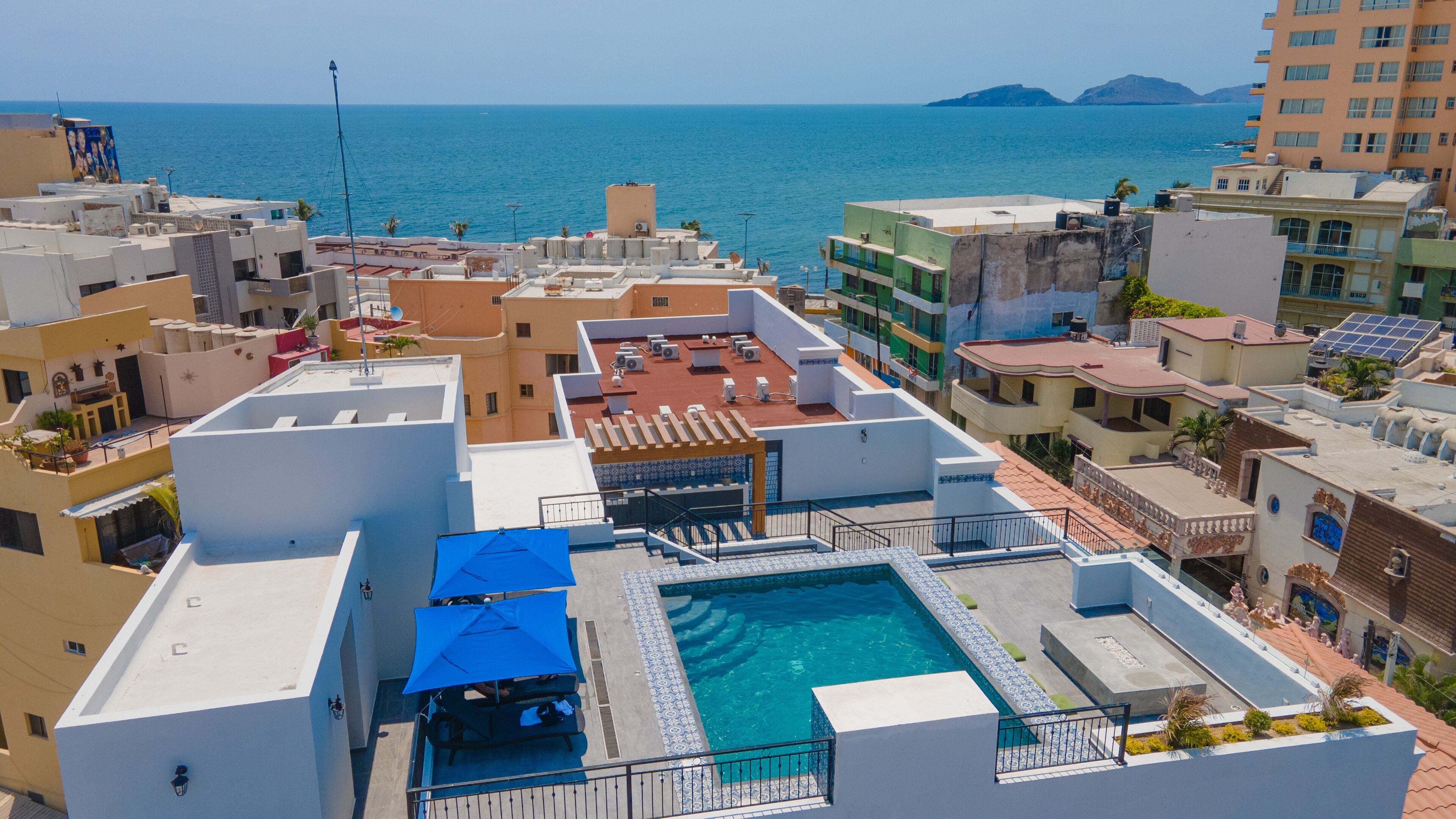 A rooftop pool with a view of the sea, surrounded by buildings with balconies and terraces.