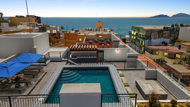 A rooftop pool with a view of the sea, surrounded by buildings. - Casa Barros Vacation Condos (Mazatlán)