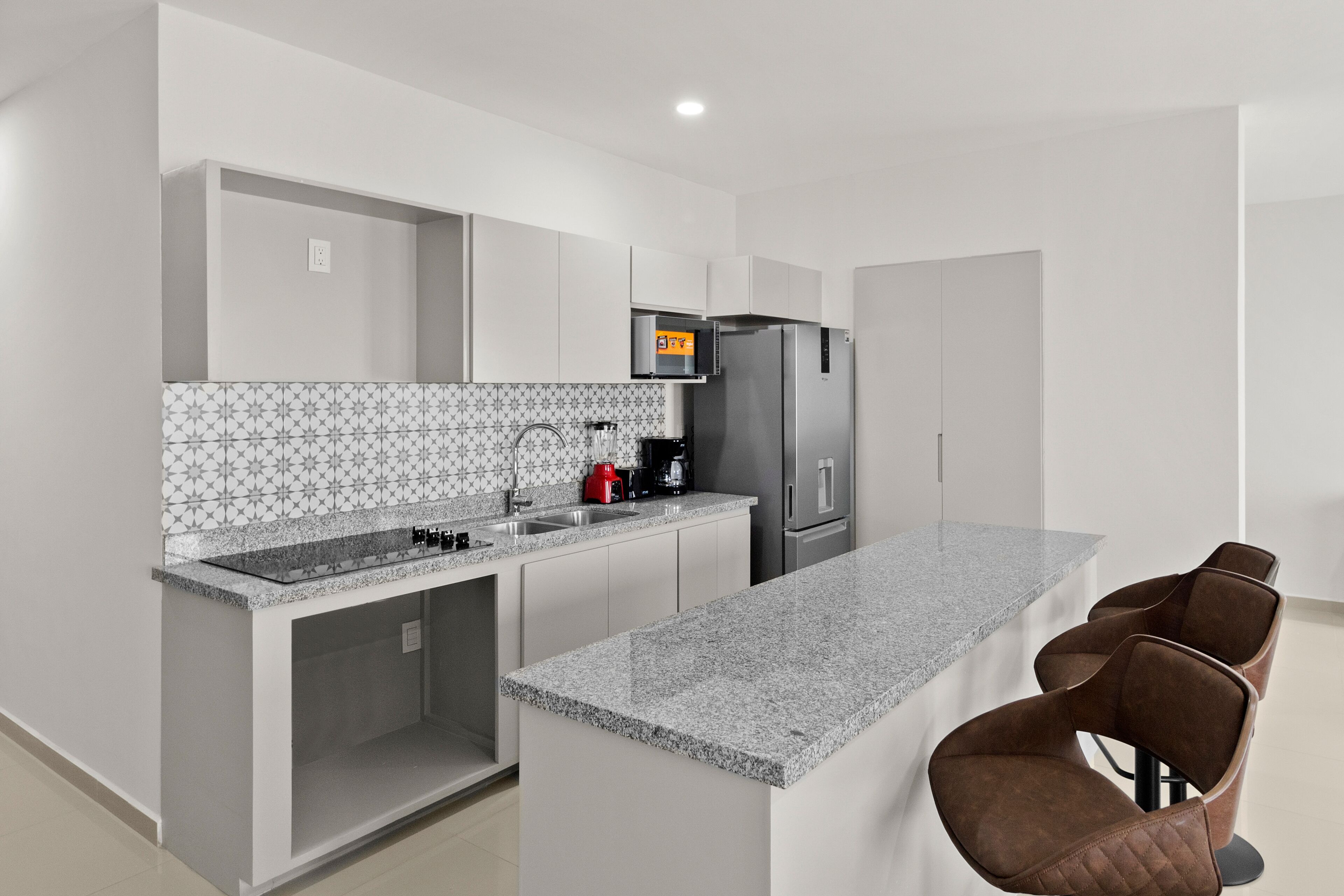 Una cocina moderna con encimera de granito, electrodomésticos de acero inoxidable y horno empotrado.