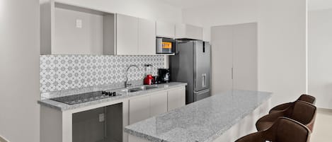 Una cocina moderna con encimera de granito, electrodomésticos de acero inoxidable y horno empotrado.