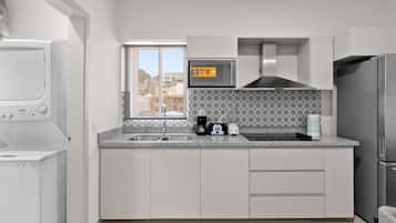 Une cuisine moderne équipée d’un lave-linge et d’un sèche-linge intégrés, d’un four à micro-ondes, d’une machine à café et d’un réfrigérateur.