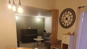 Amplia sala de estar con mesa de comedor de madera, un reloj de pared grande y una acogedora zona de estar.
