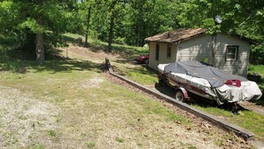 A small cabin with a covered trailer attached, surrounded by trees and a grassy area. - Lake View Cabin on Lake Norfork (Mountain Home)