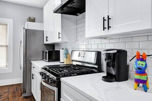 Enjoy cooking in this fully equipped kitchen with a black stove, microwave, and coffee maker.