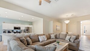Ein modernes Wohnzimmer mit einem Ecksofa, einem Couchtisch und einer Küche im Hintergrund.