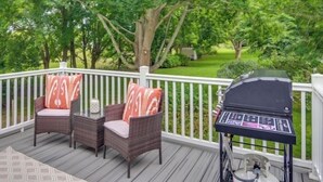 A deck with two wicker chairs, a grill, and a view of a green landscape. - Beautiful House near Beach and Castle Hill (Middletown)