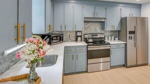 A modern kitchen with light blue cabinets, stainless steel appliances, and a marble backsplash. - Beautiful House near Beach and Castle Hill (Middletown)