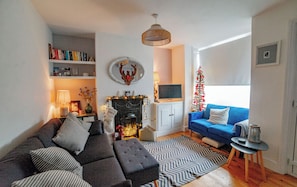 Una sala de estar con un sofá, una chimenea, un televisor, un árbol de Navidad y una estantería.