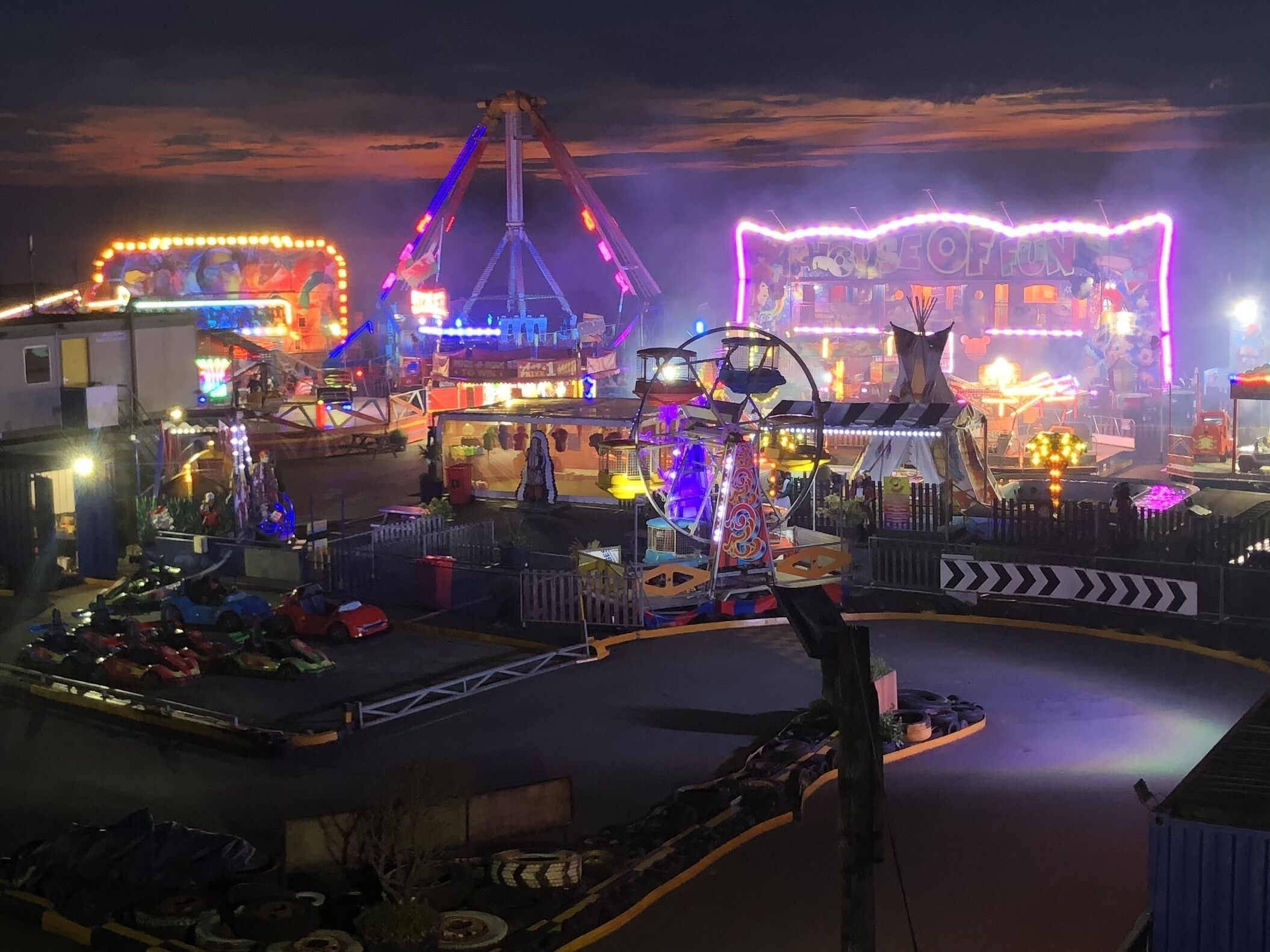 Een themapark 's nachts, met verschillende attracties en achtbanen.