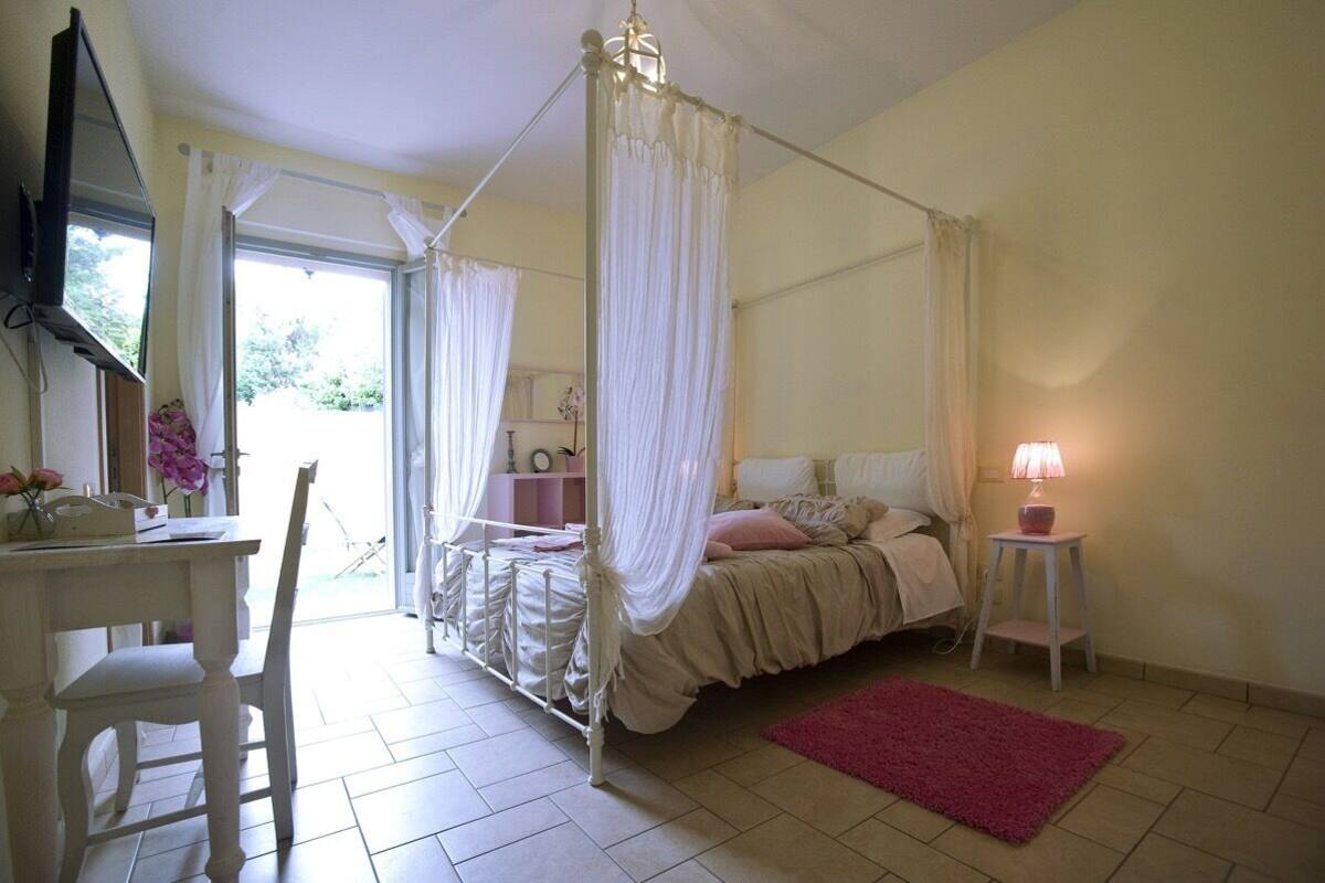 Une chambre à coucher avec un lit à baldaquin, un bureau avec une chaise, une petite table avec une lampe et un tapis rouge.