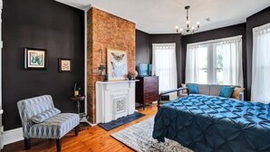 Ein Schlafzimmer mit einem großen Bett, einem Kamin, einer Couch und einem Schreibtisch.