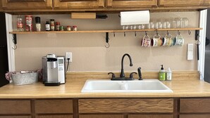 A kitchen with wooden cabinets, a coffee maker, and a sink.