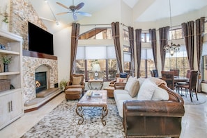 A living room with a fireplace, leather furniture, and a television mounted on the wall. - Charlie's Slopeside: Arrowhead Ski-In/Out, Steps to Lift, Sleeps 8, Heated Pool + Hot Tub (Edwards)