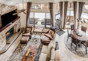 A spacious living room with a fireplace, leather sofas, a coffee table, and a dining area with a round table and chairs.